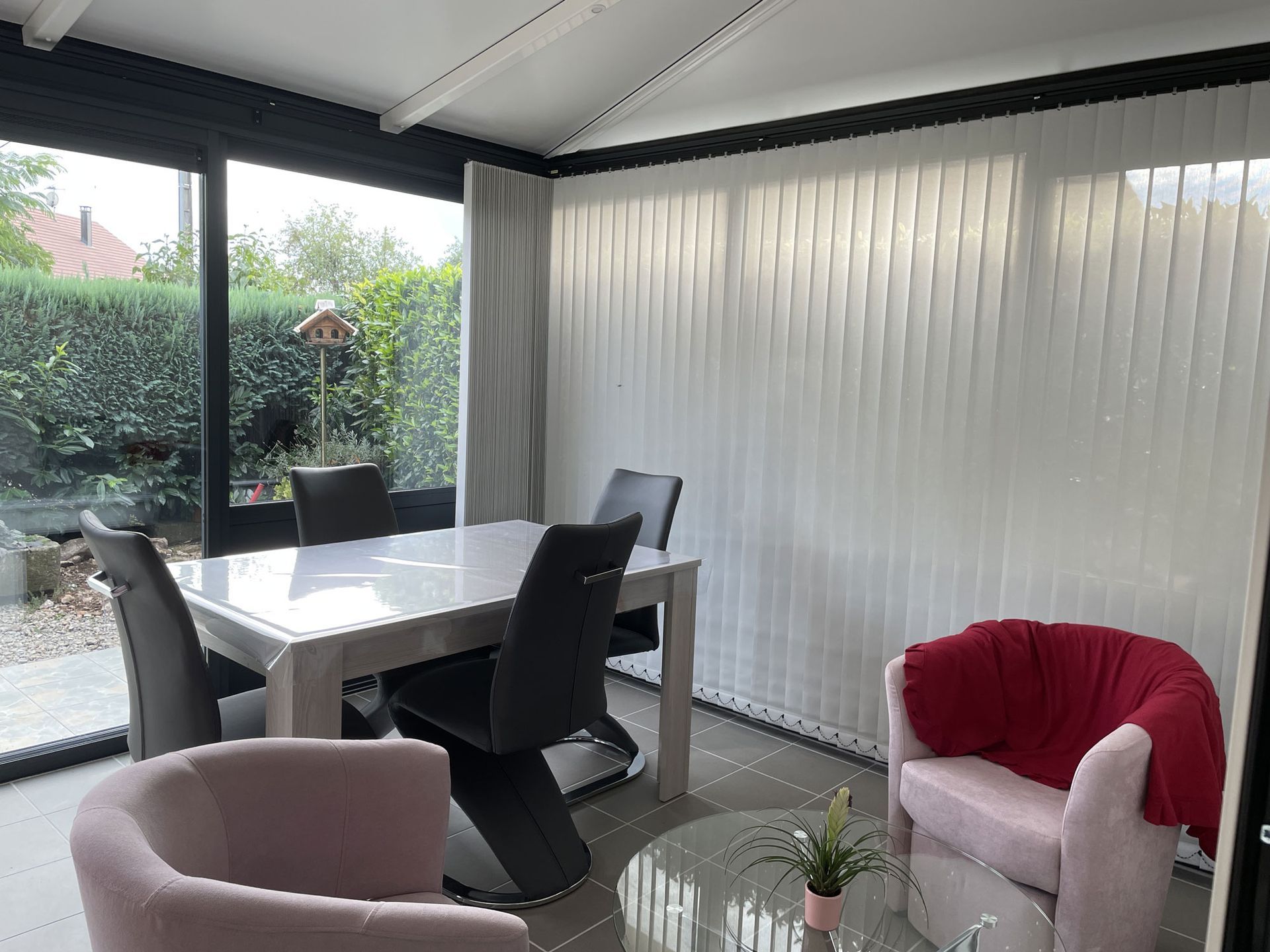 Véranda aménagée comme pièce de vie avec des stores verticaux fermés