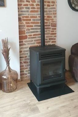 Poêle à bois noir devant un mur en briques