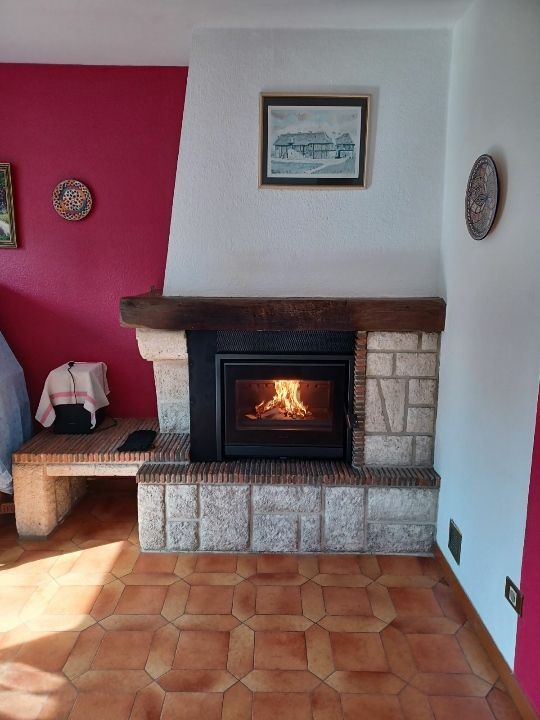 Une cheminée dans une pièce avec un mur rouge.