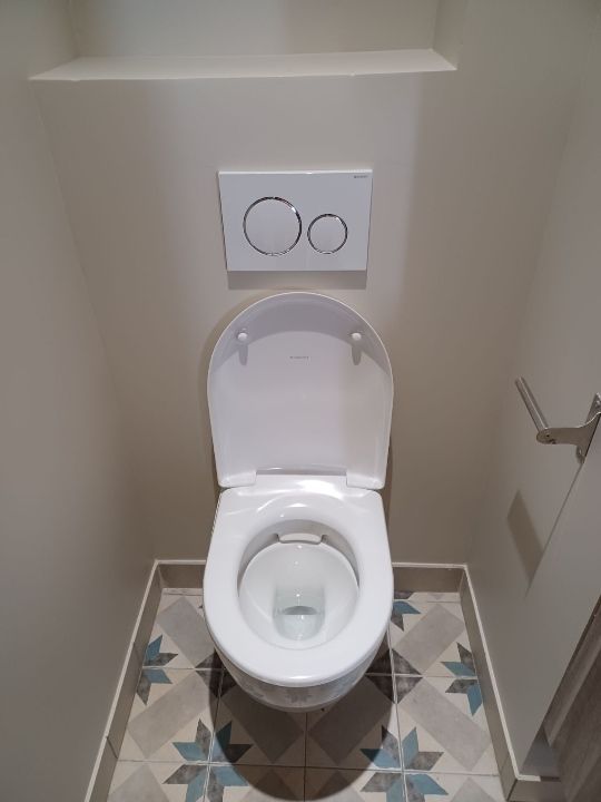 WC blanc ouvert avec carrelage à motifs