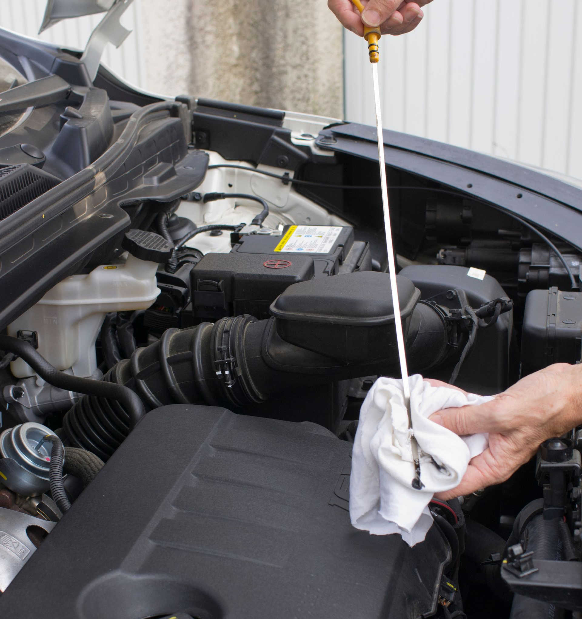 Vérification du niveau d'huile moteur à l'aide d'une jauge, compartiment moteur visible.