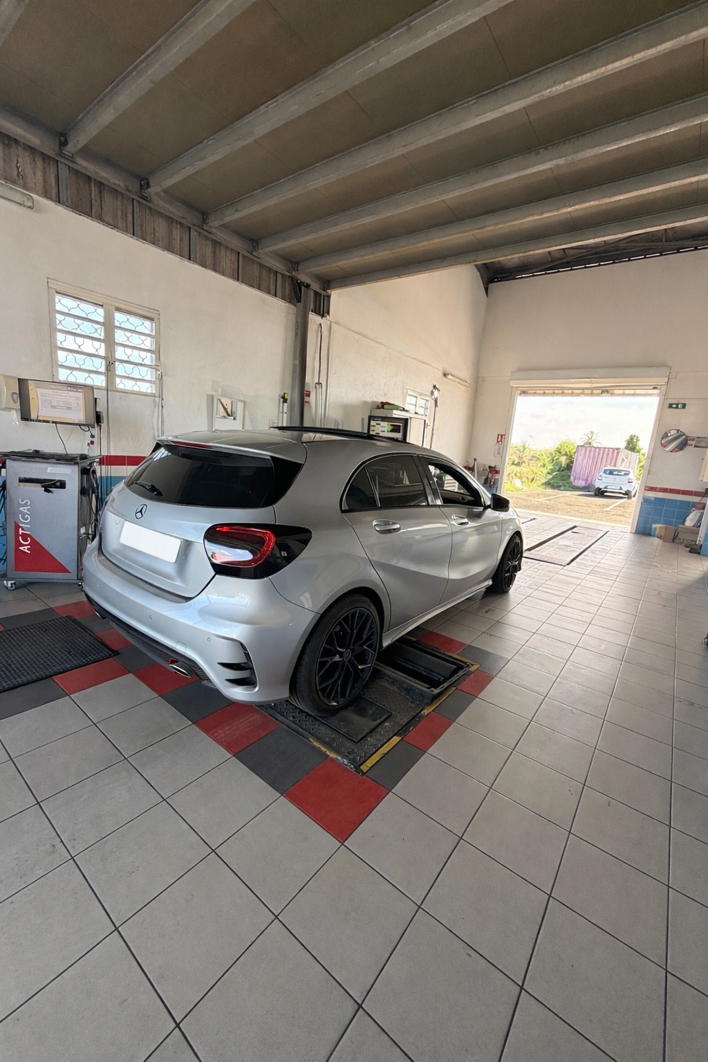 Une Mercedes-Benz à hayon garée dans un atelier automobile bien éclairé, au sol carrelé.