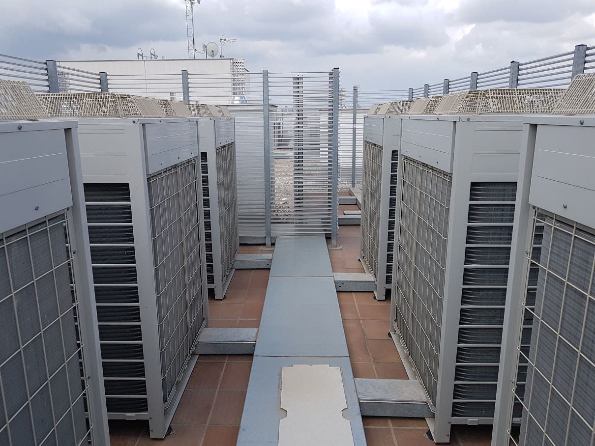 Una fila de aparatos de aire acondicionado están alineados en la parte superior de un edificio.