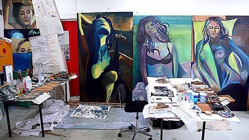 Un estudio de pintura con muchos cuadros en la pared.