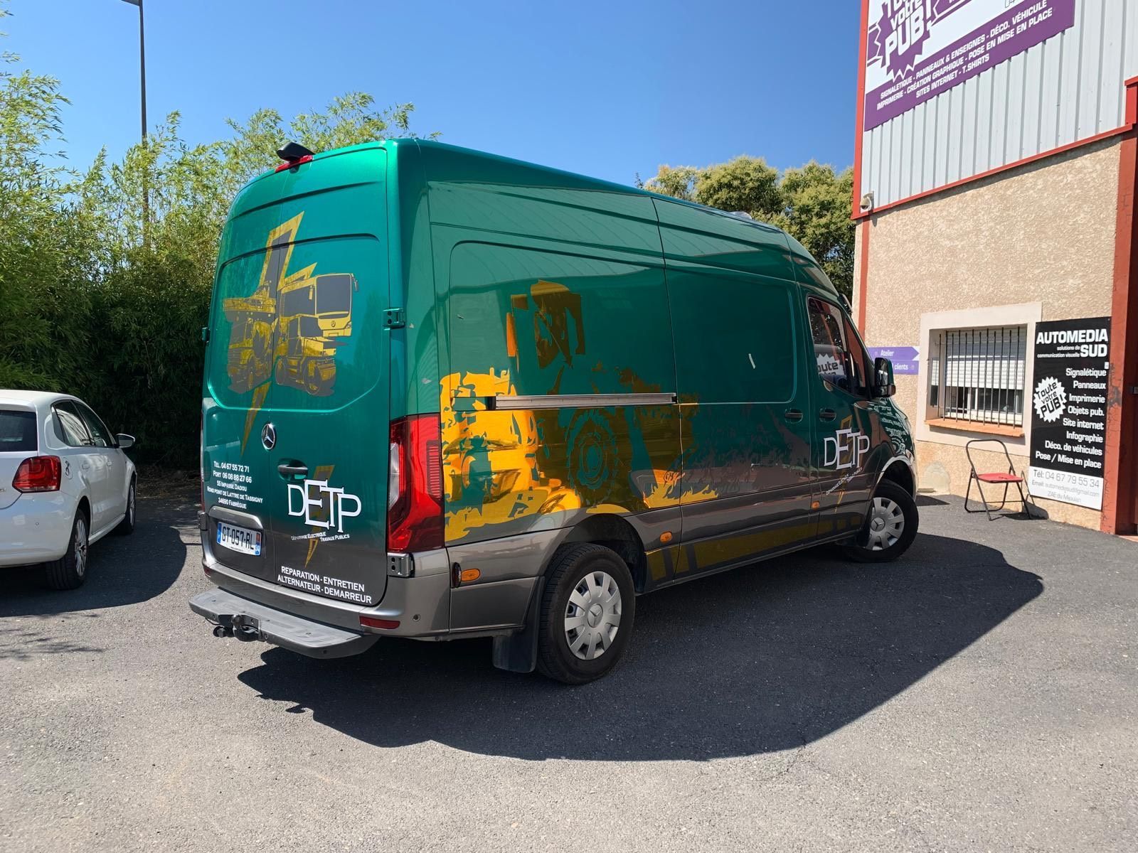 Camionnette de livraison verte et orange garée à côté d'un entrepôt en plein soleil