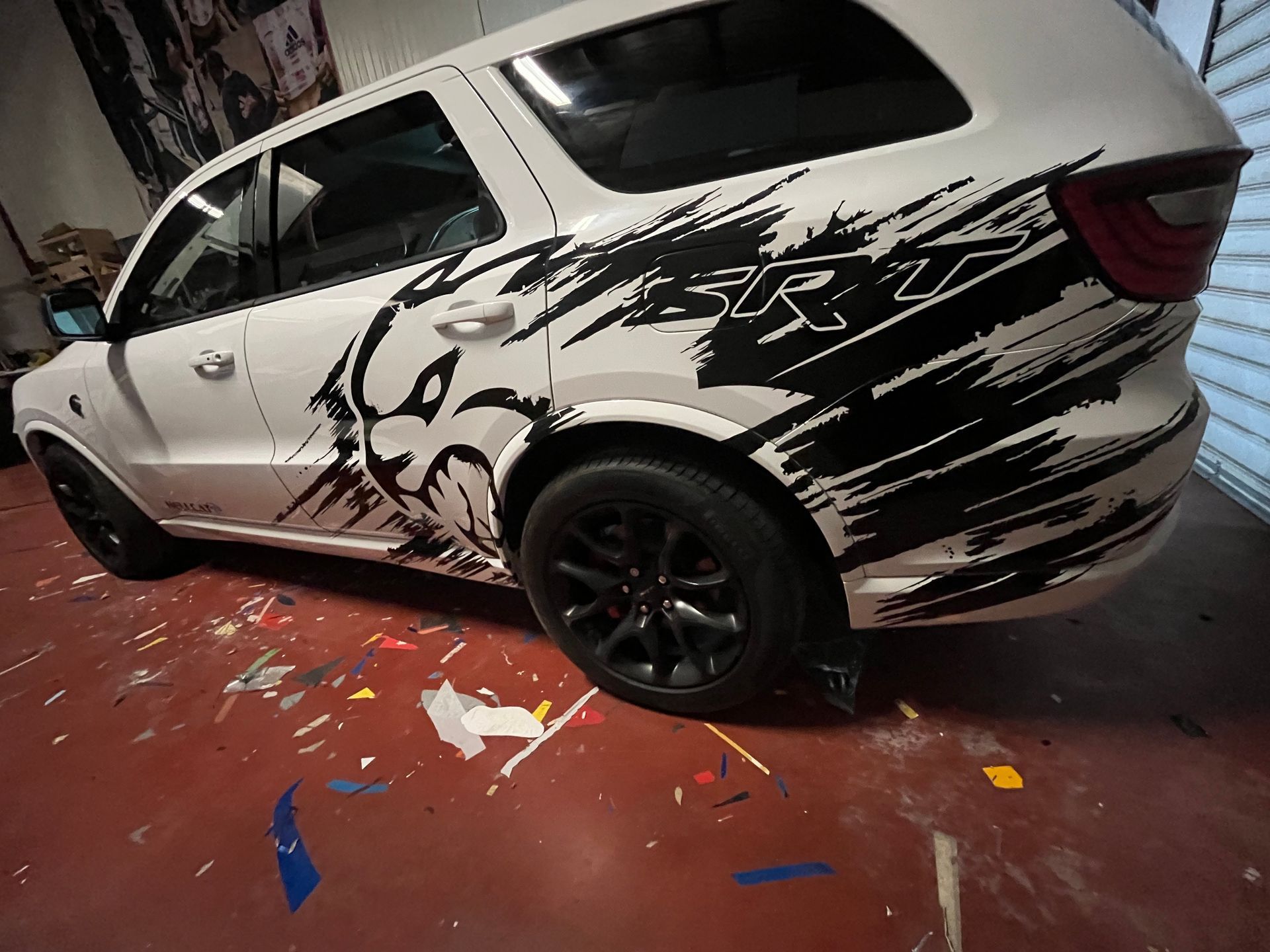 Voiture blanche avec des autocollants noirs de style graffiti dans un garage.