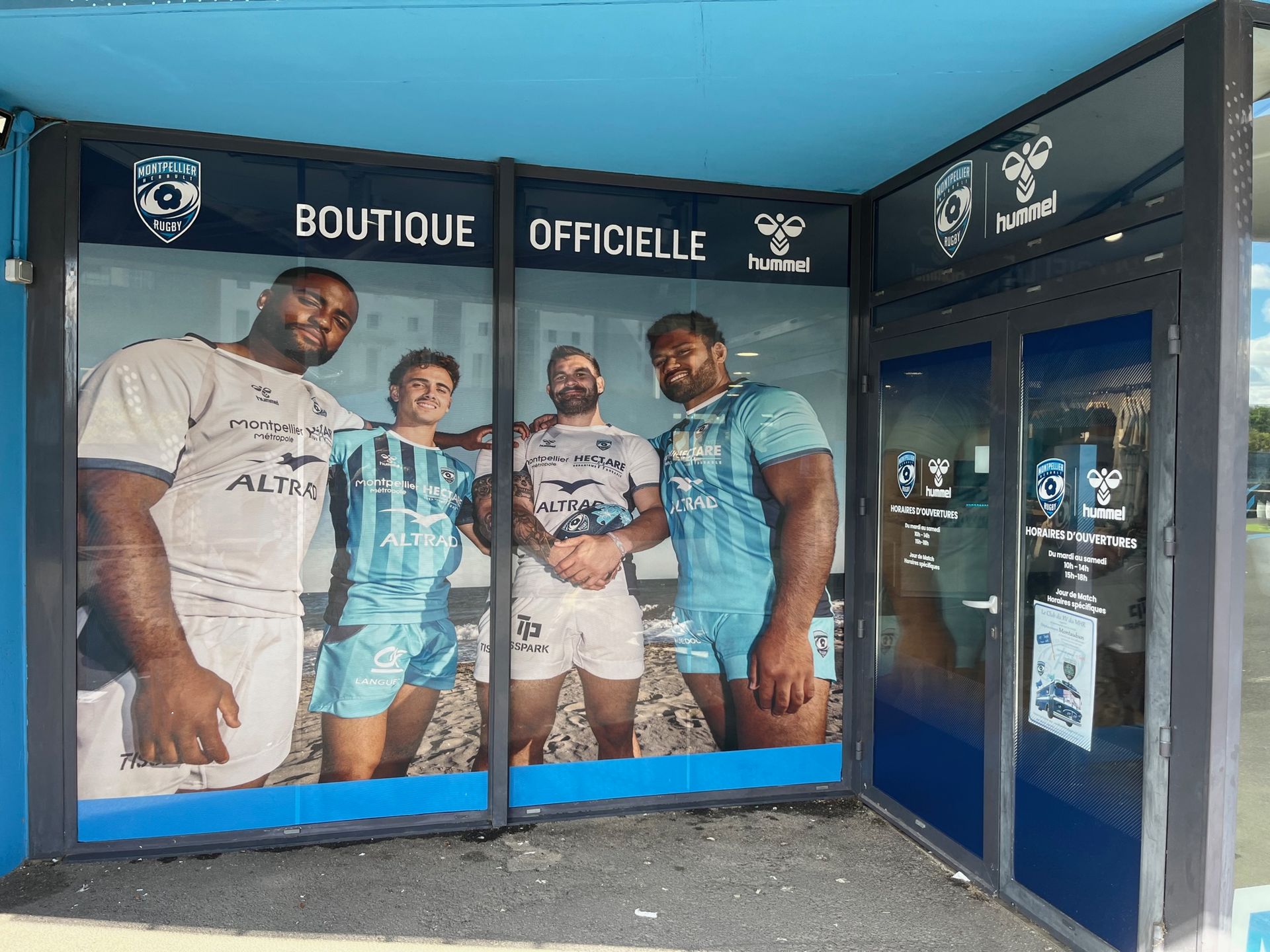 Façade de boutique de club de football avec de grandes affiches de joueurs et une enseigne française.