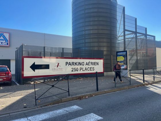 Panneau de parking avec flèche vers la gauche à l'extérieur d'un bâtiment moderne, indiquant 250 places.