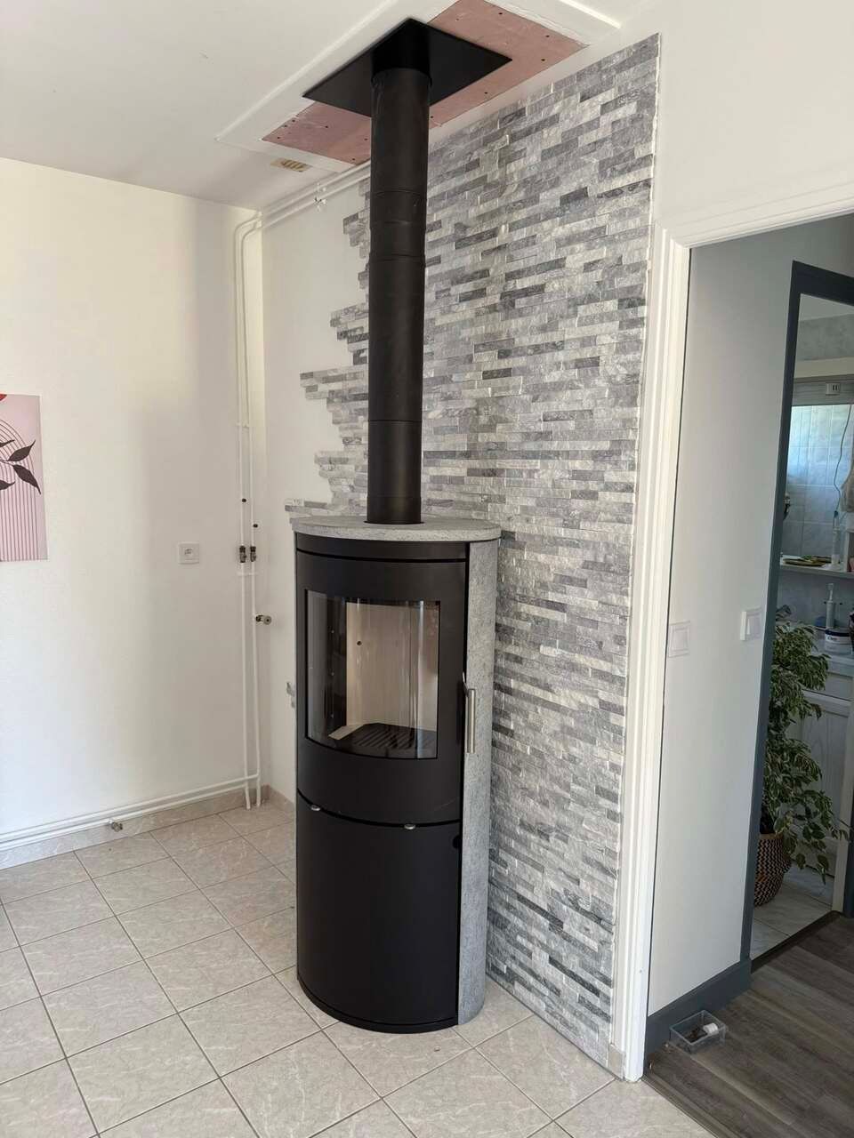 Poêle à bois noir avec cheminée, installé contre un mur.