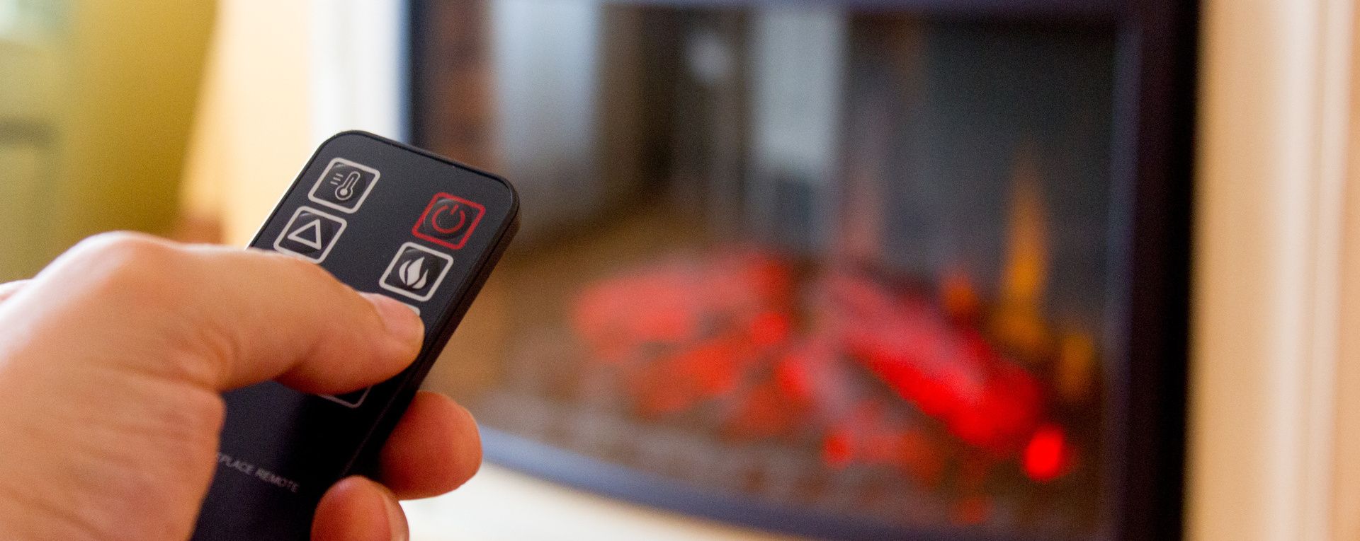 Une main tenant une télécommande pointée vers un poêle.