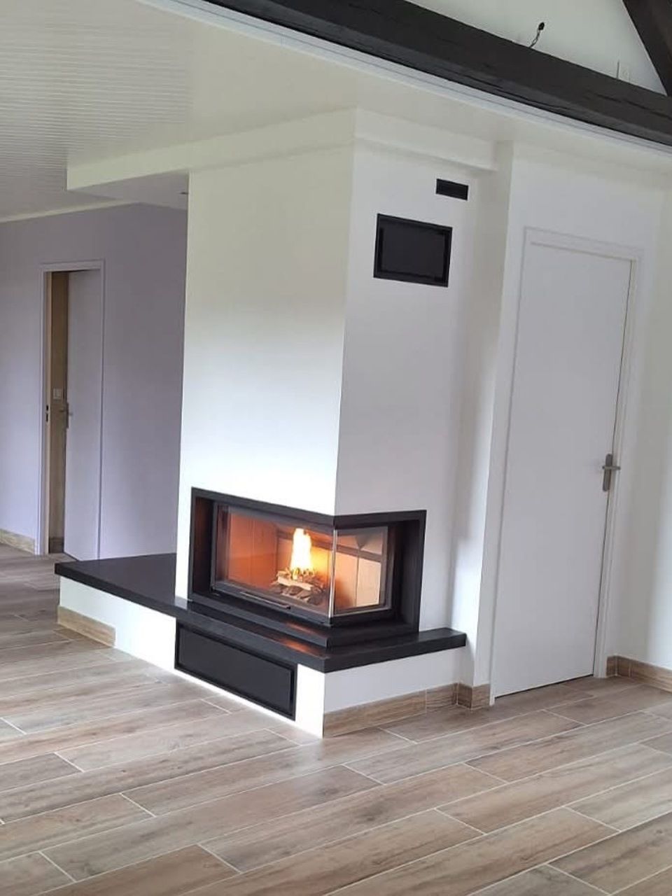 Cheminée d'angle avec feu allumé.