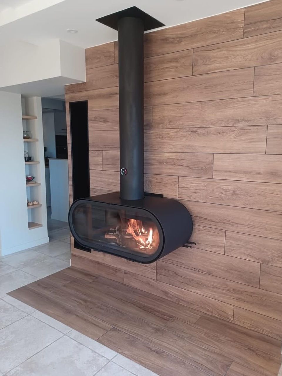 Cheminée moderne avec un conduit noir, fixée sur un mur lambrissé.