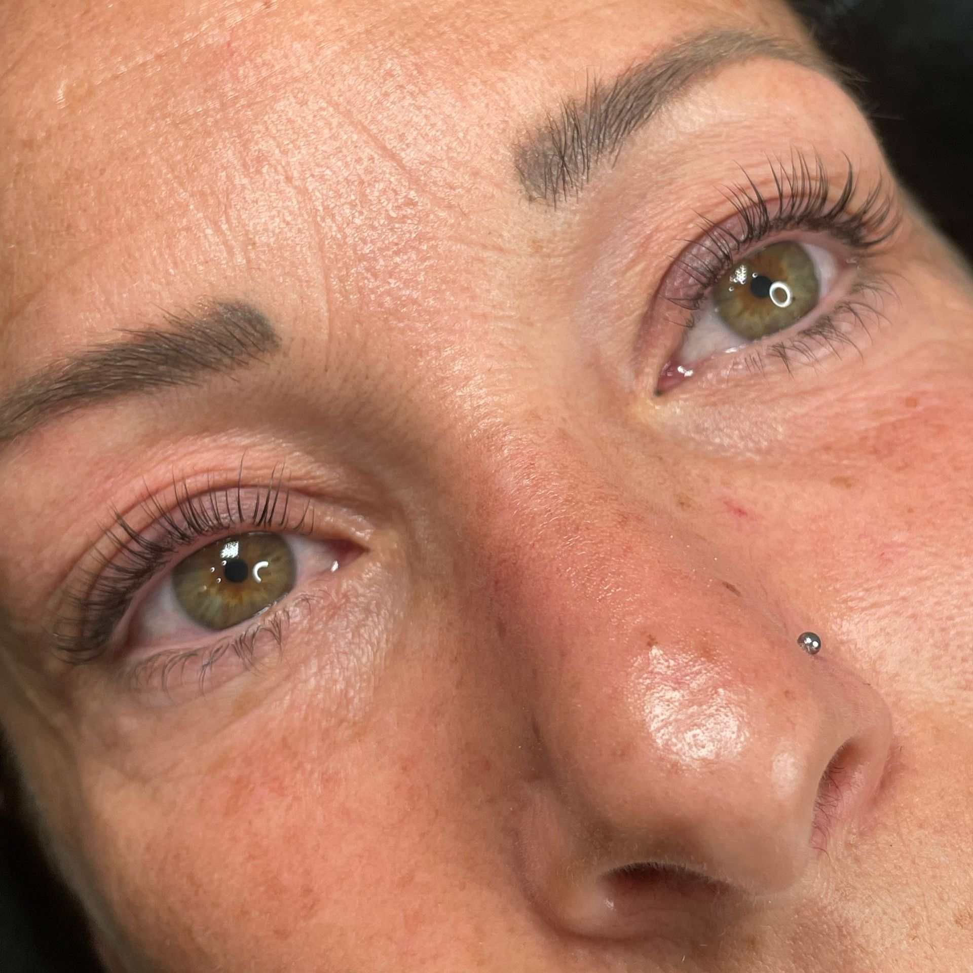 Un primer plano del rostro de una mujer con ojos verdes y un anillo en la nariz.