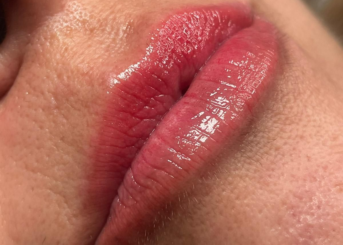 Un primer plano de los labios de una mujer con lápiz labial rosa y dientes blancos.