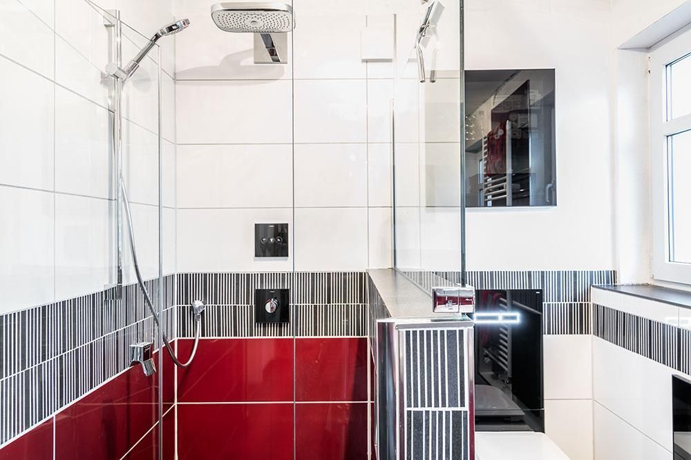 Ein Badezimmer mit roten und weißen Fliesen und einer ebenerdigen Dusche.
