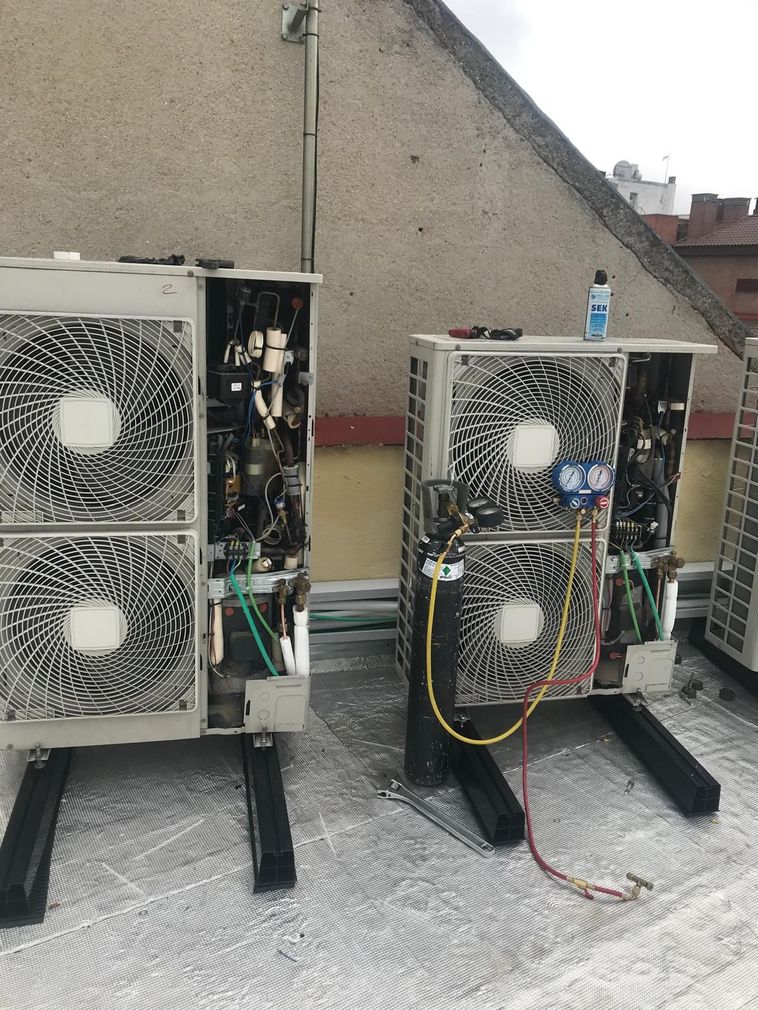 Un par de aparatos de aire acondicionado están colocados encima de un tejado.