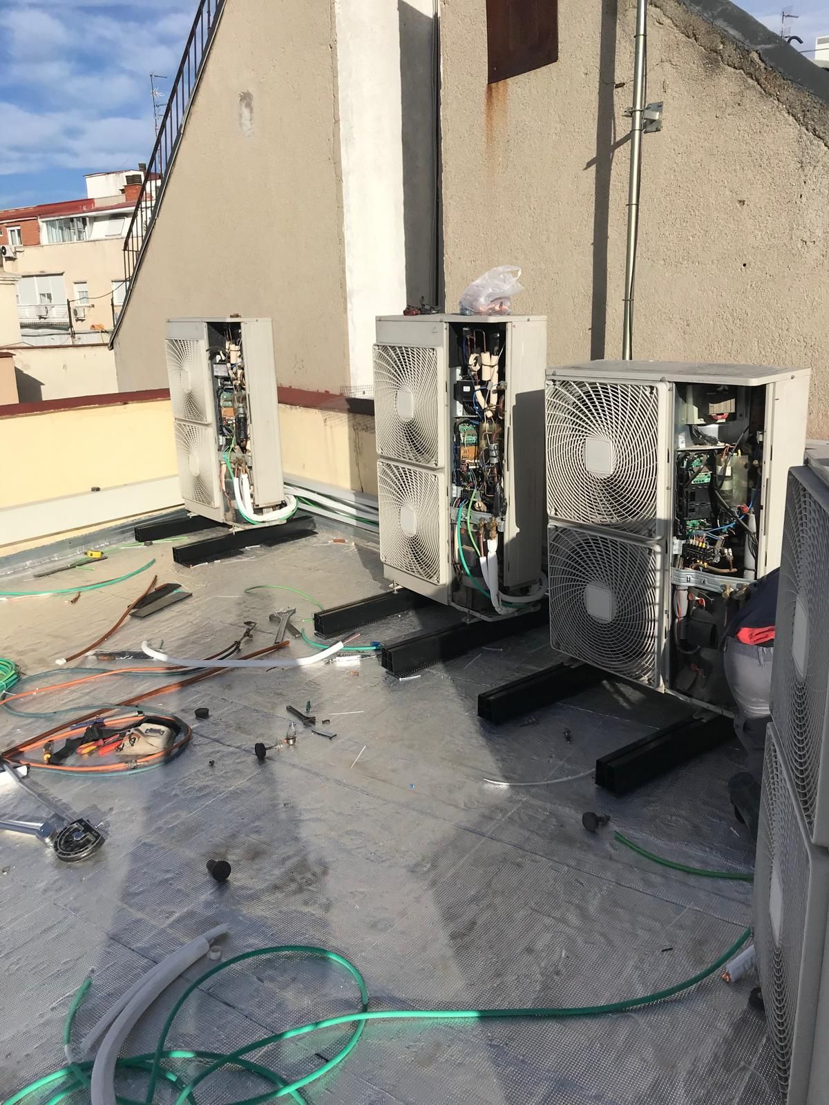 Tres aparatos de aire acondicionado están situados en el tejado de un edificio.