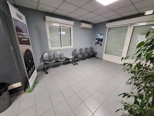 Salle d'attente avec chaises grises, fenêtres et banderole.
