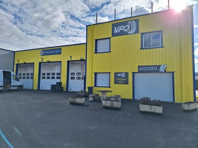 Un magasin de pneus jaune avec trois portes de garage.