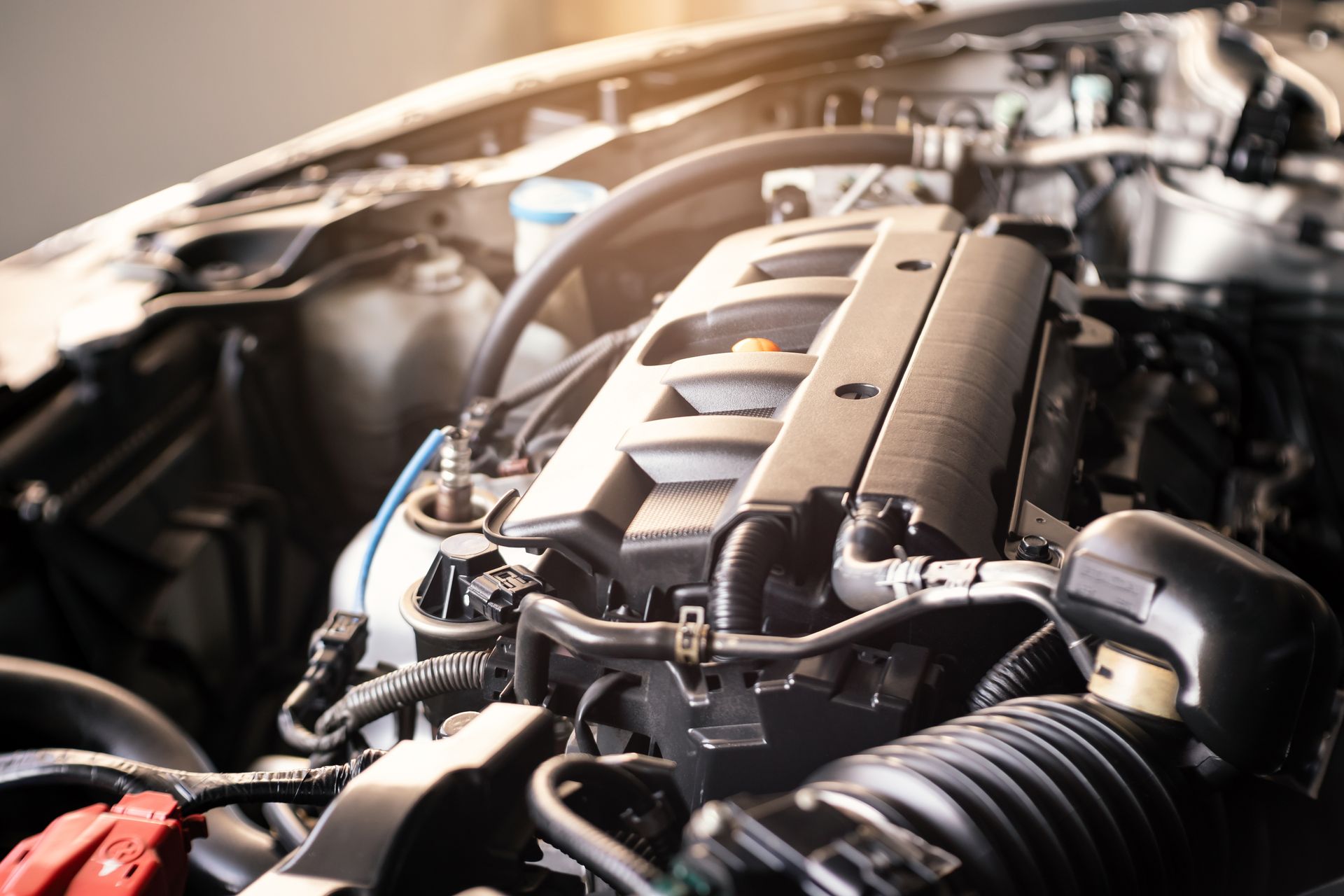 Moteur de voiture, noir avec de nombreux tubes et câbles, dans un compartiment moteur ouvert.