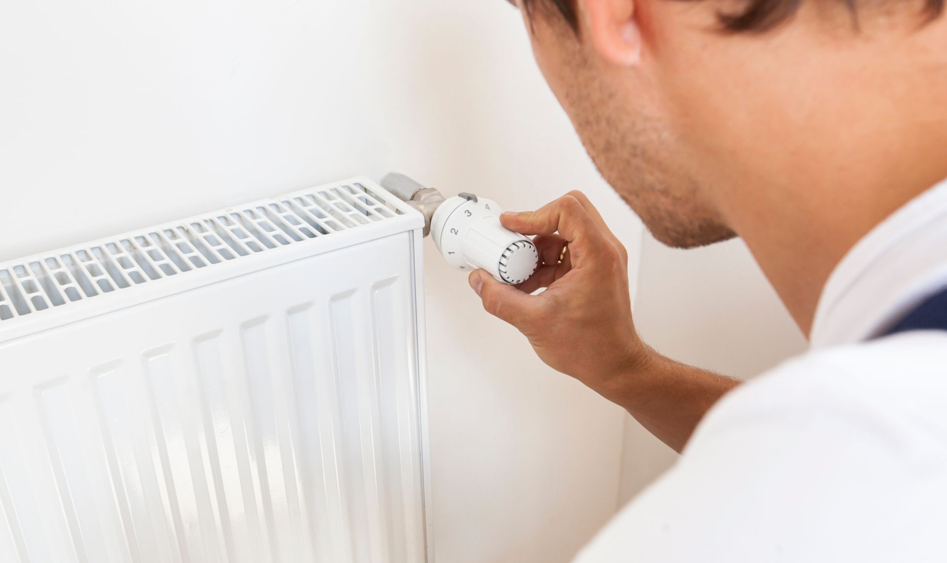 Photo d'un plombier qui règle la vanne d'un radiateur