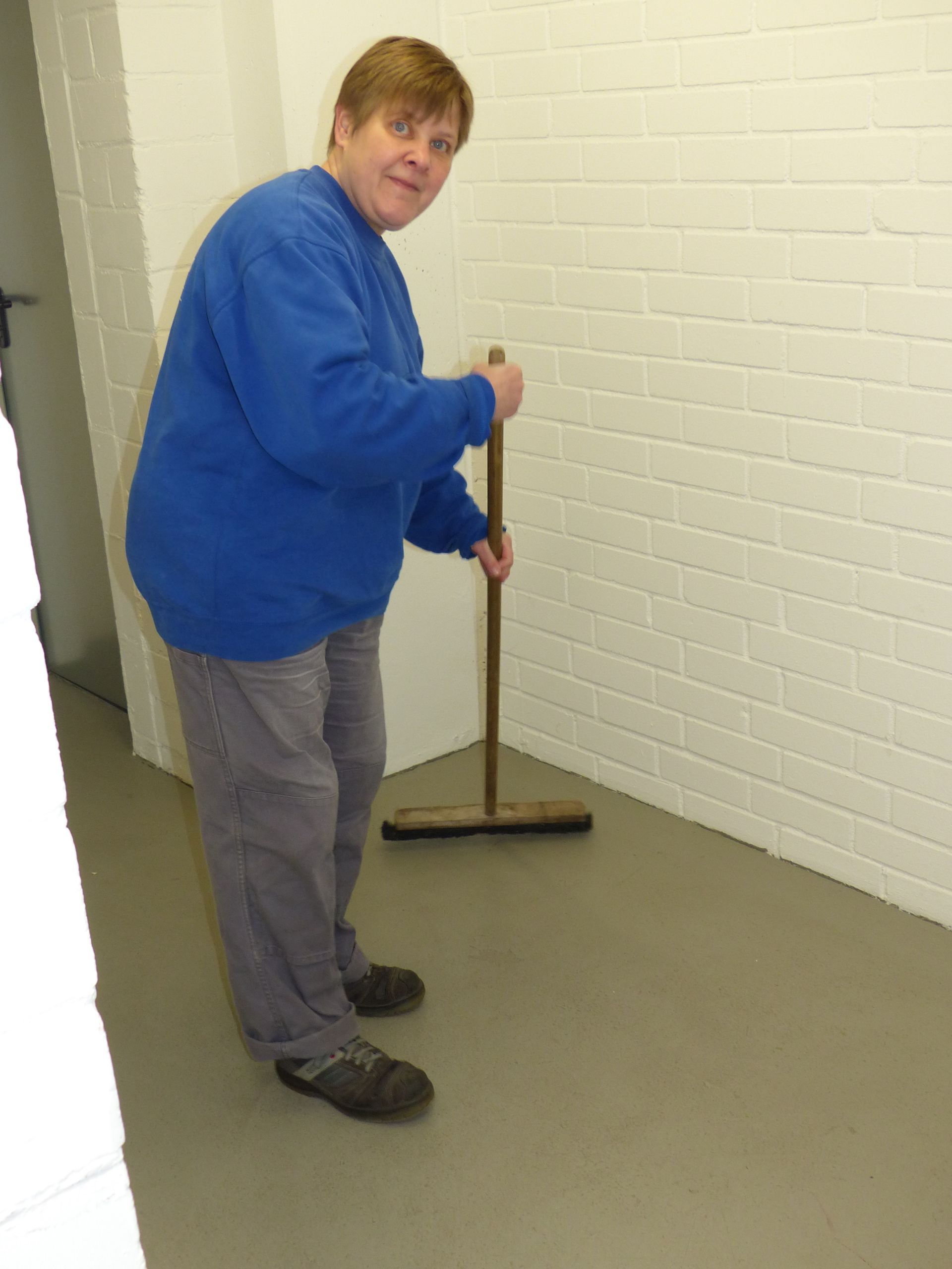 Ein Mann in einem blauen Pullover fegt den Boden