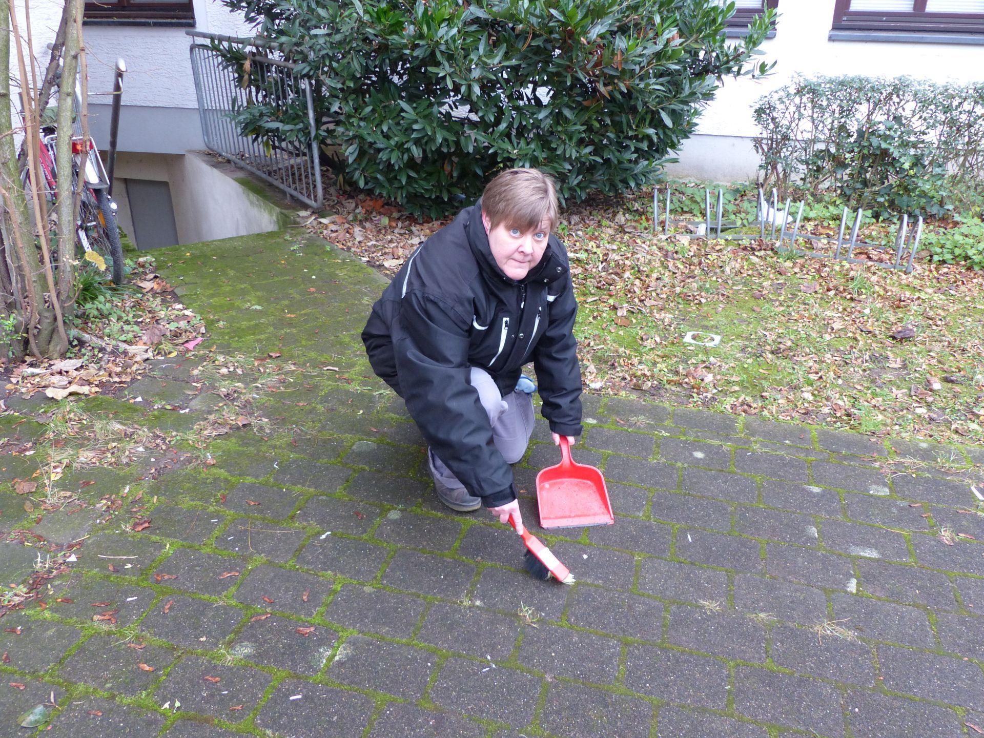 Eine Frau fegt den Boden mit einer roten Schaufel