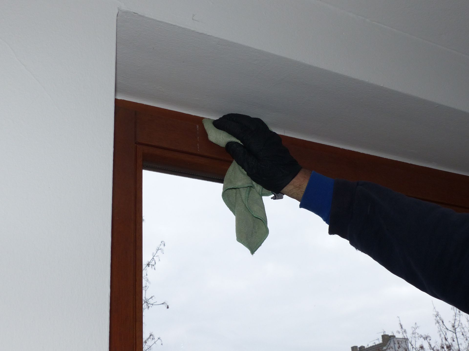 Eine Person putzt ein Fenster mit einem Tuch