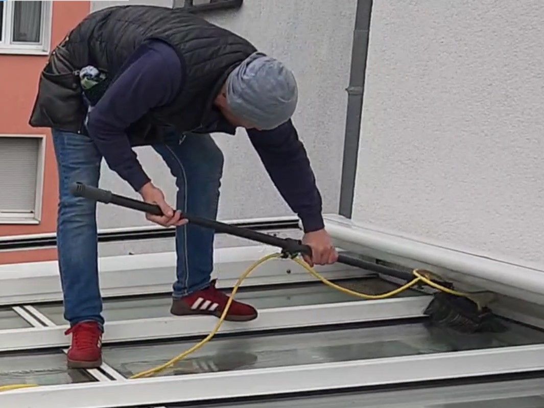 Ein Mann reinigt ein Dach mit einem Besen.