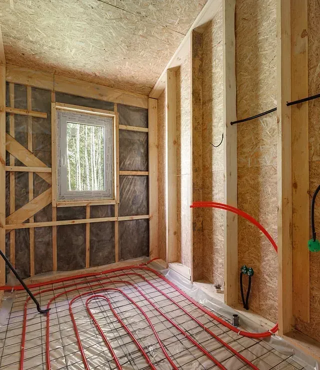Una habitación con una ventana y tuberías rojas en el suelo.