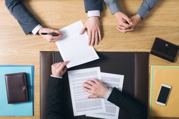 Dokumente werden am Tisch von drei Personen besprochen