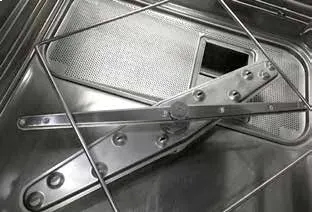 El piso interior de un lavavajillas de acero inoxidable, donde se aprecian el brazo rociador 