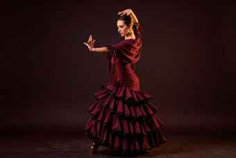 Bailaora con vestido clásico y mantón en un estudio oscuro con luz cálida