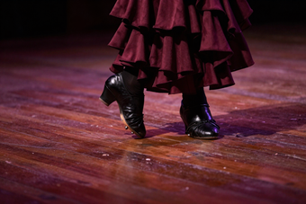 Primer plano de los pies de una bailaora de flamenco sobre un escenario de madera