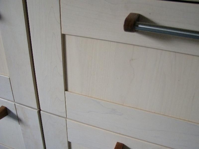 Eine Nahaufnahme eines weißen Schranks mit Holzgriffen