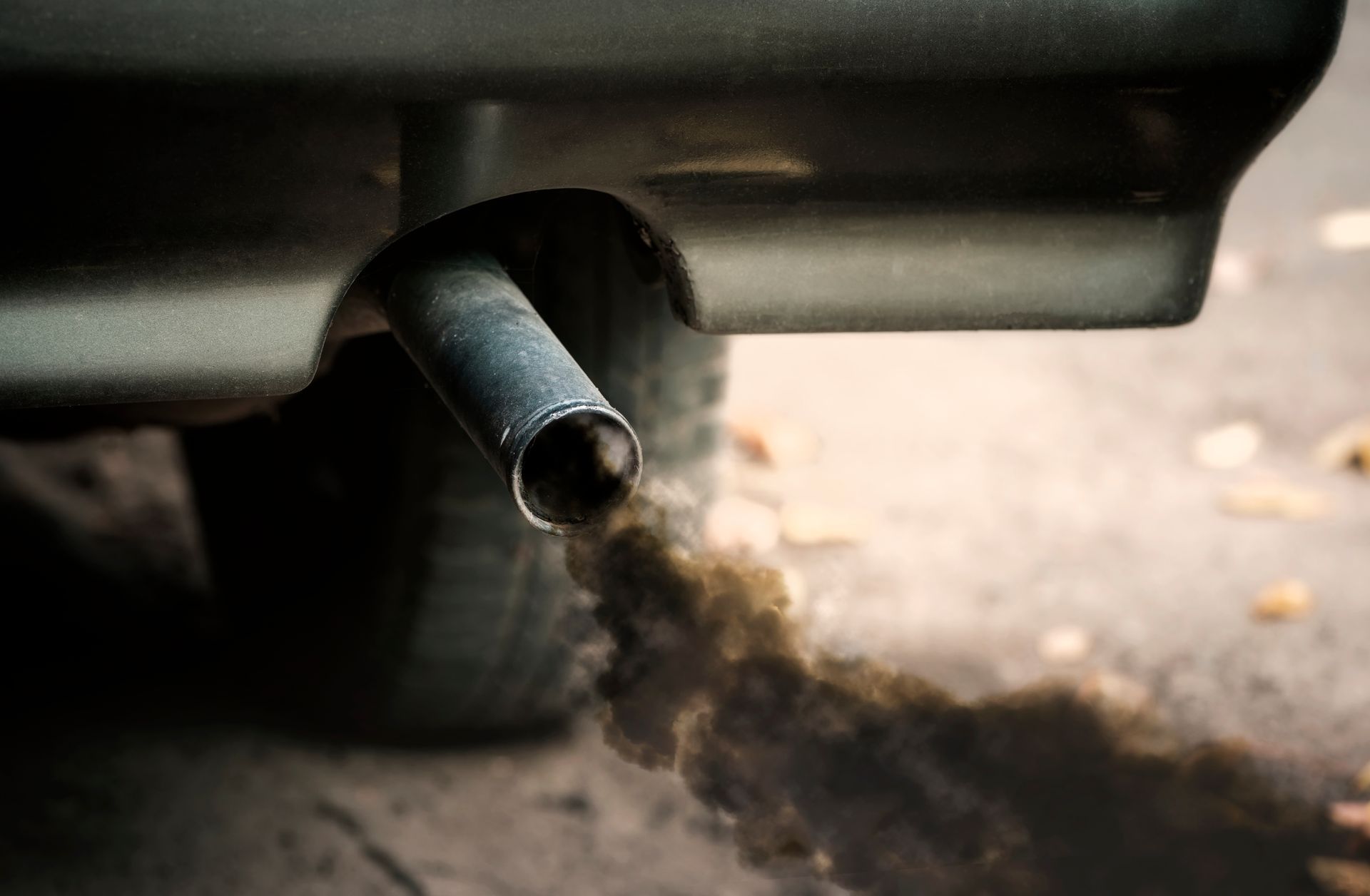 Un pot d'échappement de voiture avec de la fumée noire à la sortie.