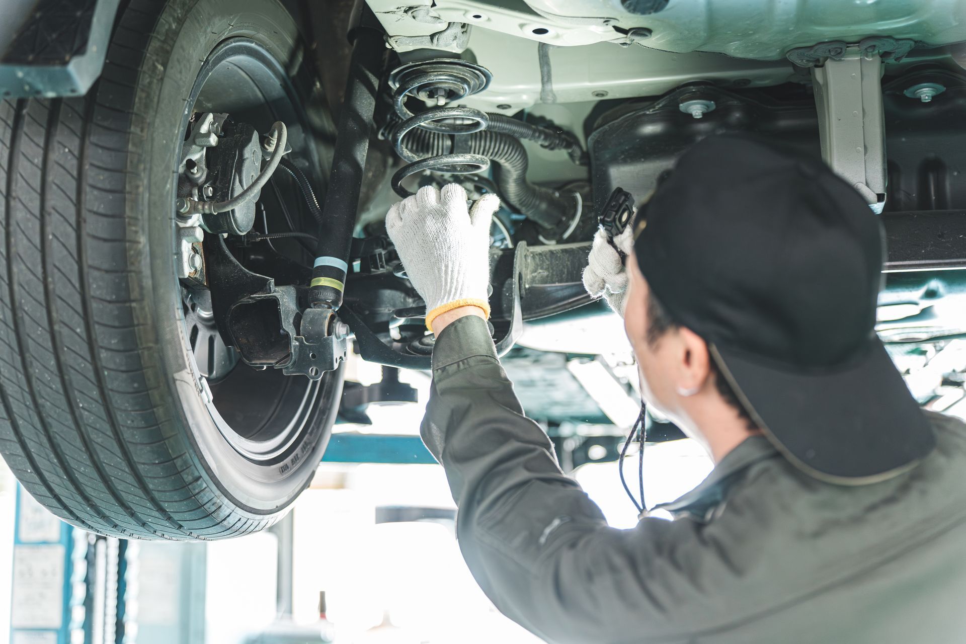 Un technicien inspecte la suspension d'une voiture sous un véhicule.