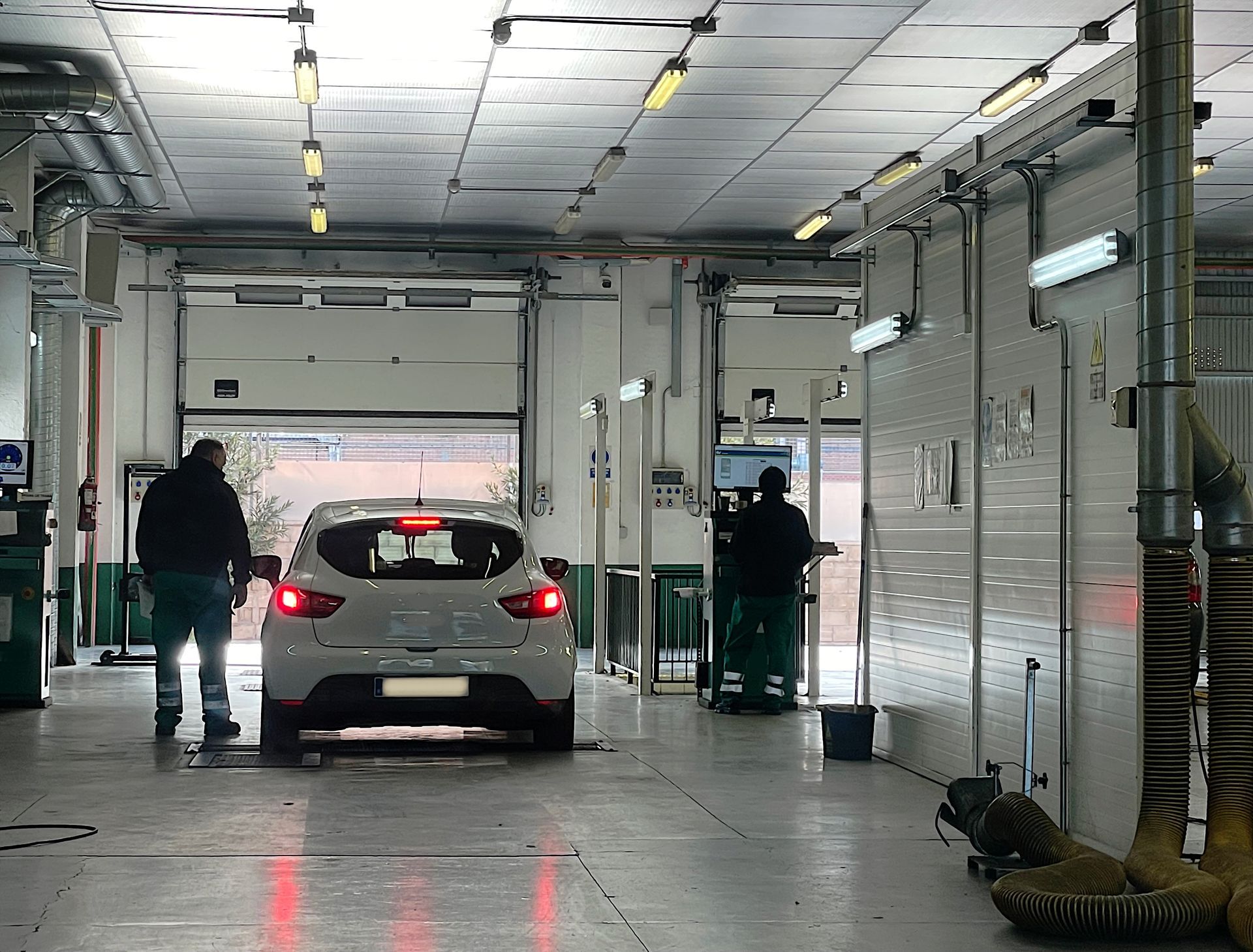 Une voiture dans un centre de contrôle technique avec des techniciens.