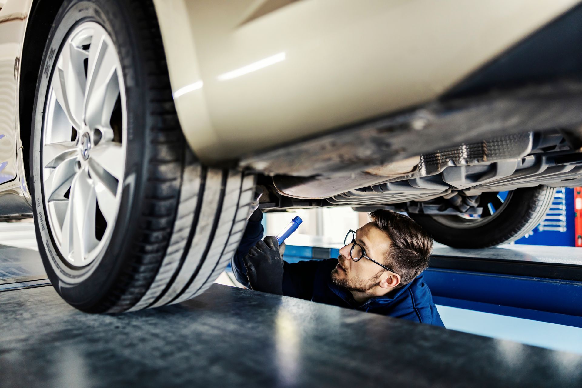 Un technicien qui inspecte le dessous d'une voiture.