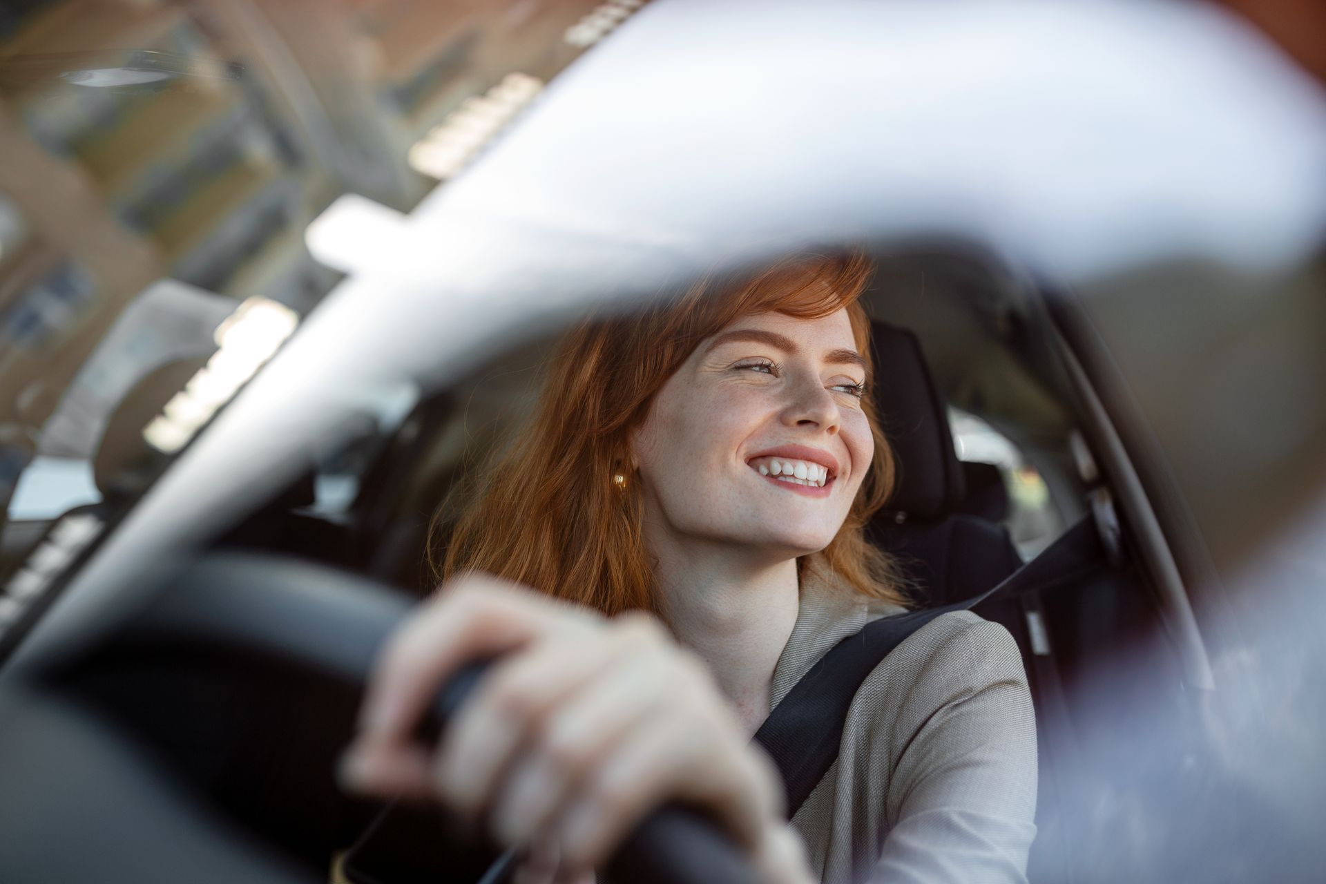 Une femme souriante au volant d'une voiture.
