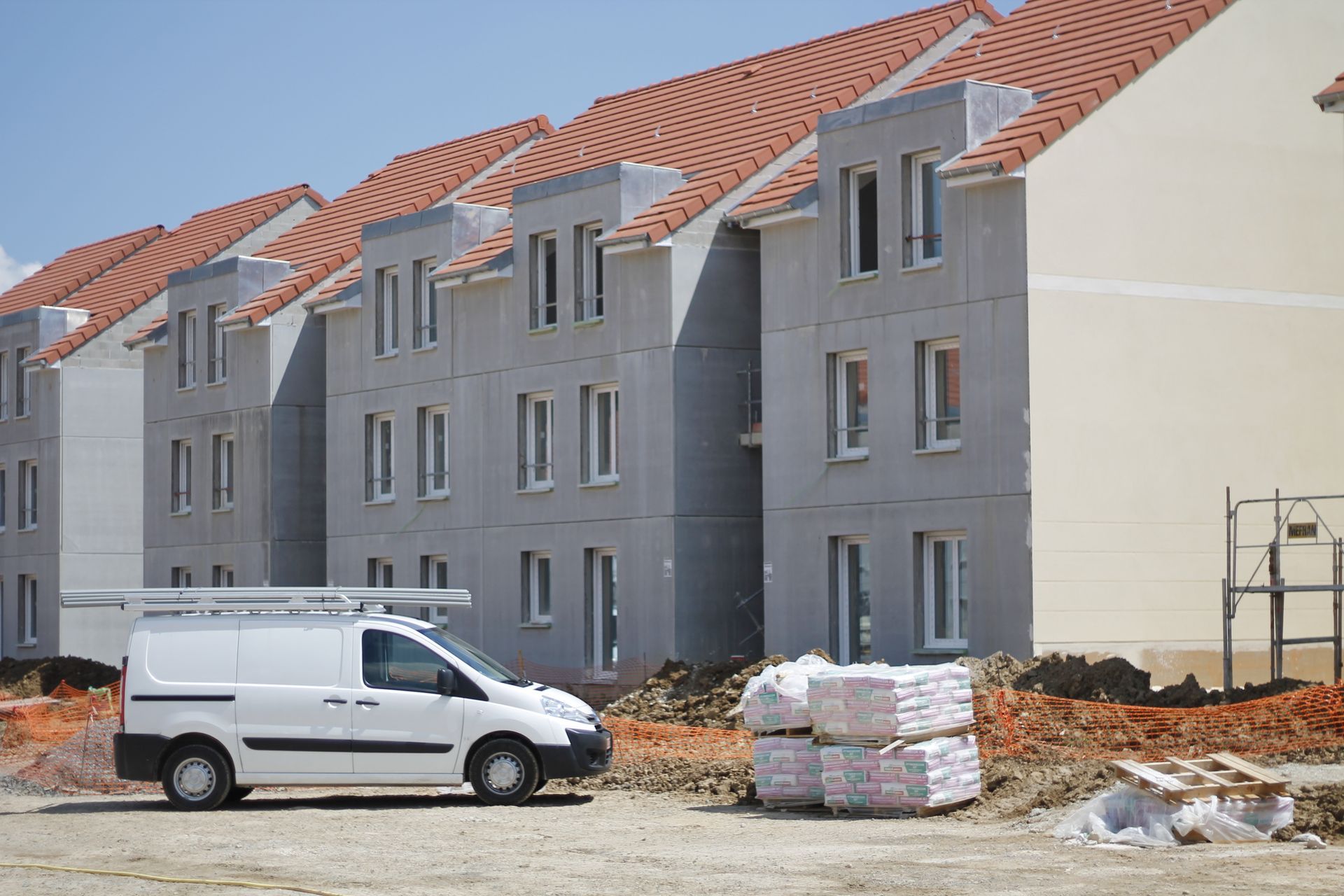 Un utilitaire stationné sur un chantier avec des bâtiments en construction.