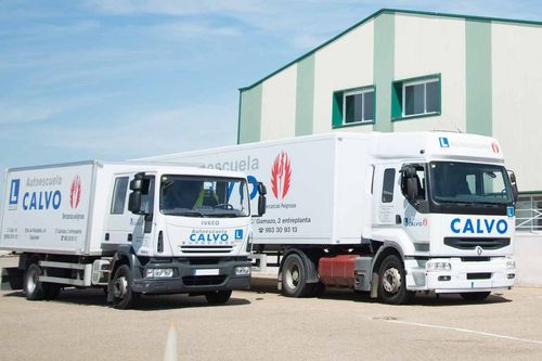 Dos camiones de reparto de CALVO aparcados frente a un almacén en un día soleado