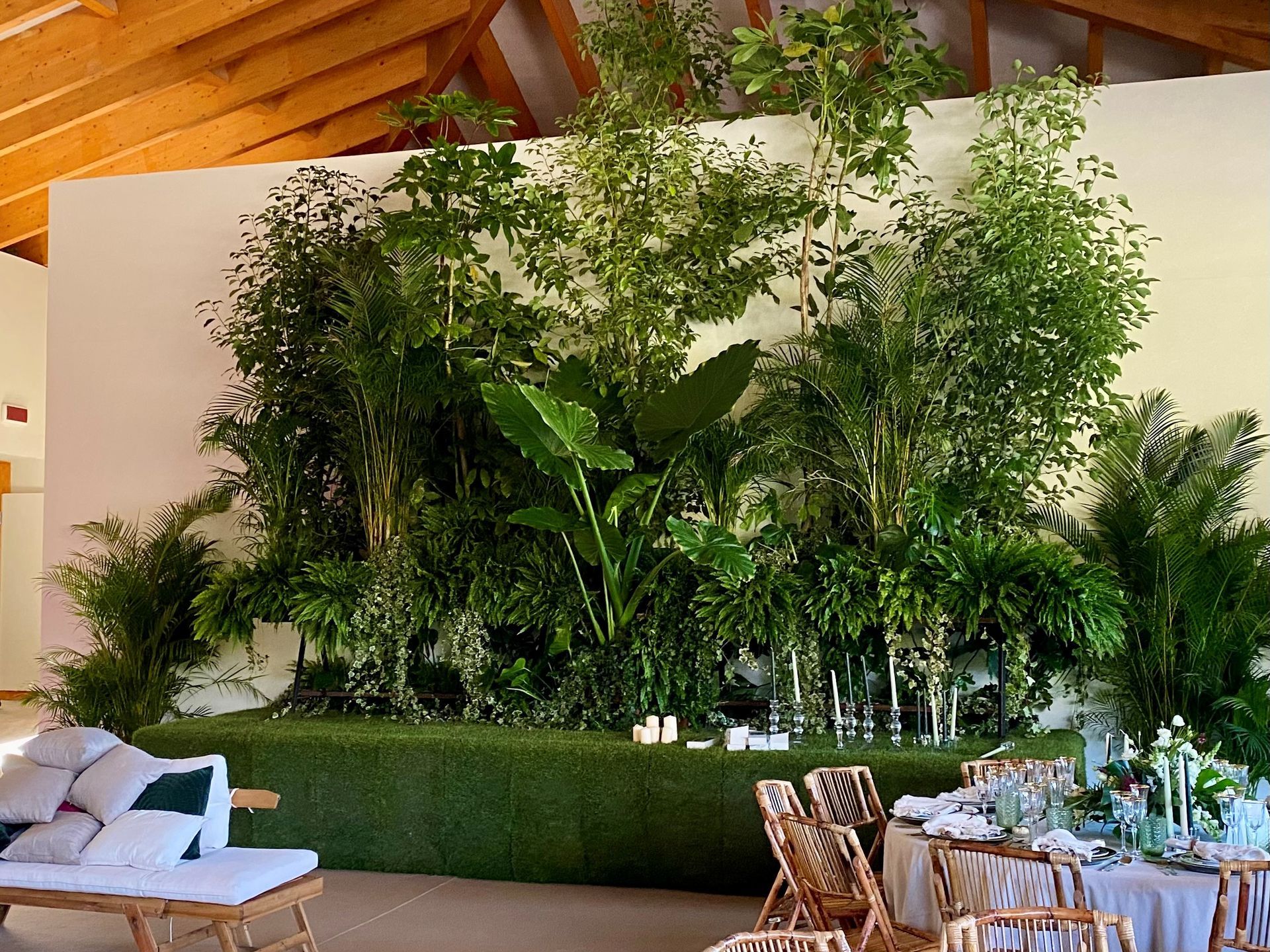 Uma sala com mesas e cadeiras e uma parede de plantas.