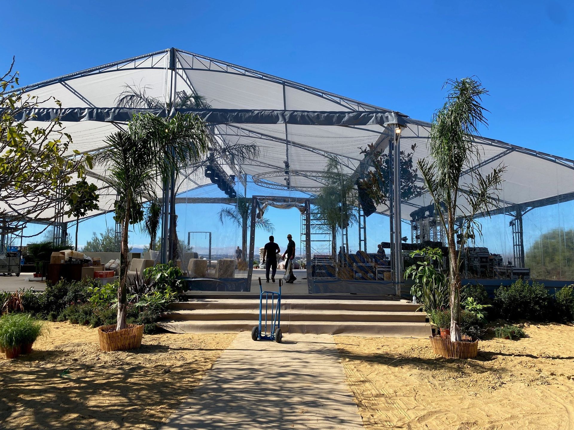 Um grupo de pessoas está de pé sob uma tenda transparente.