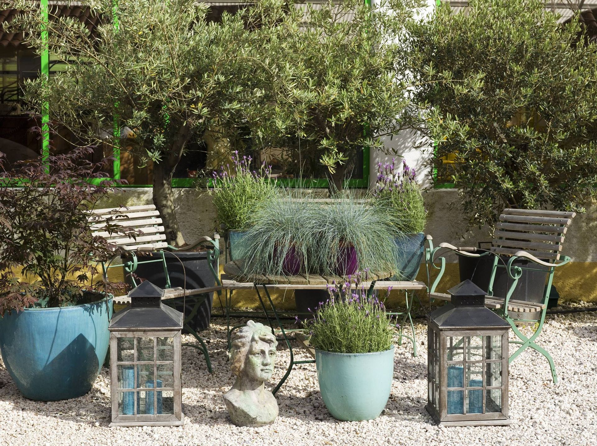 Há muitas plantas em vasos e lanternas no jardim.