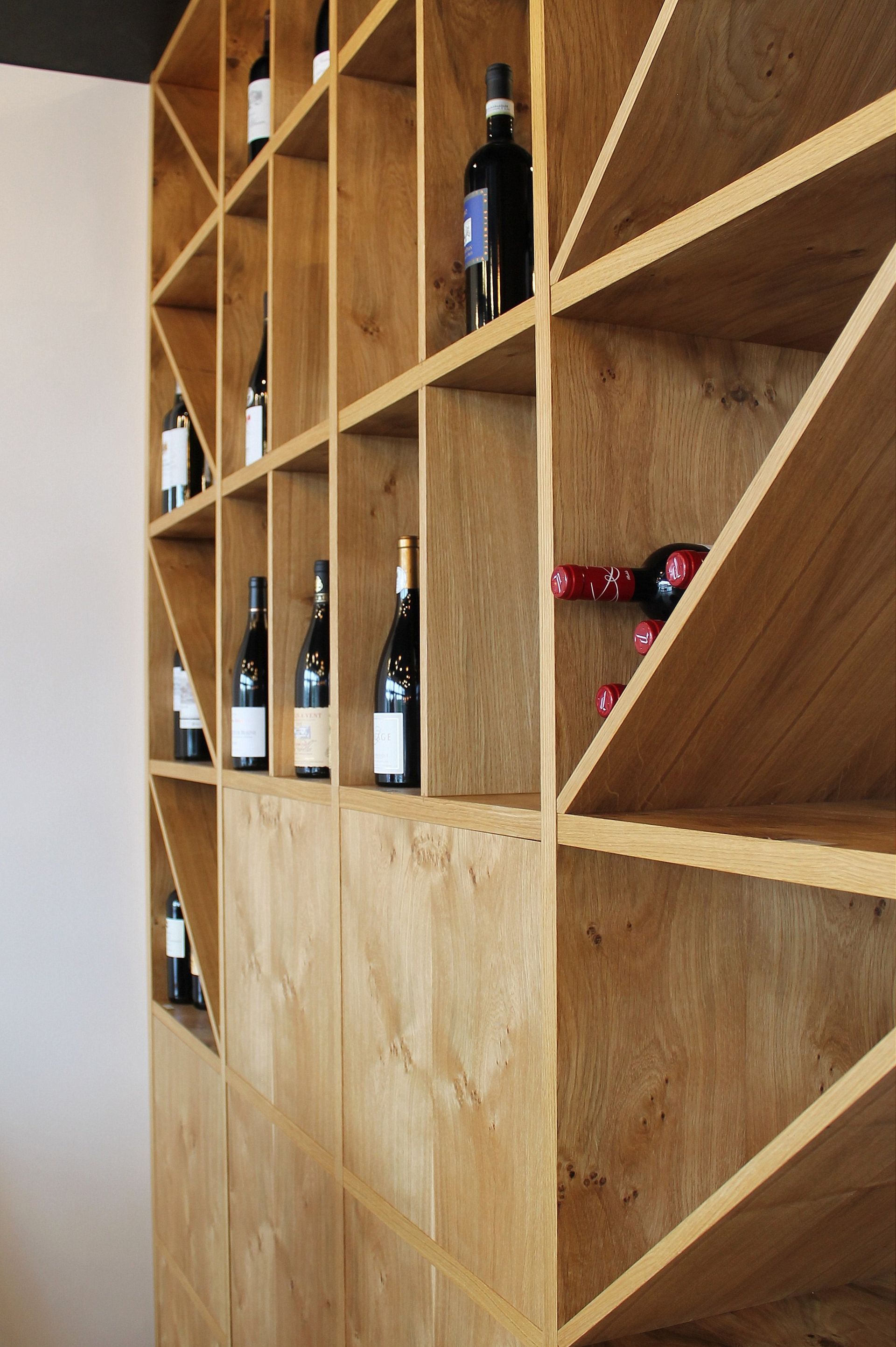 Casier à vin en bois avec bouteilles rangées dans des compartiments géométriques.