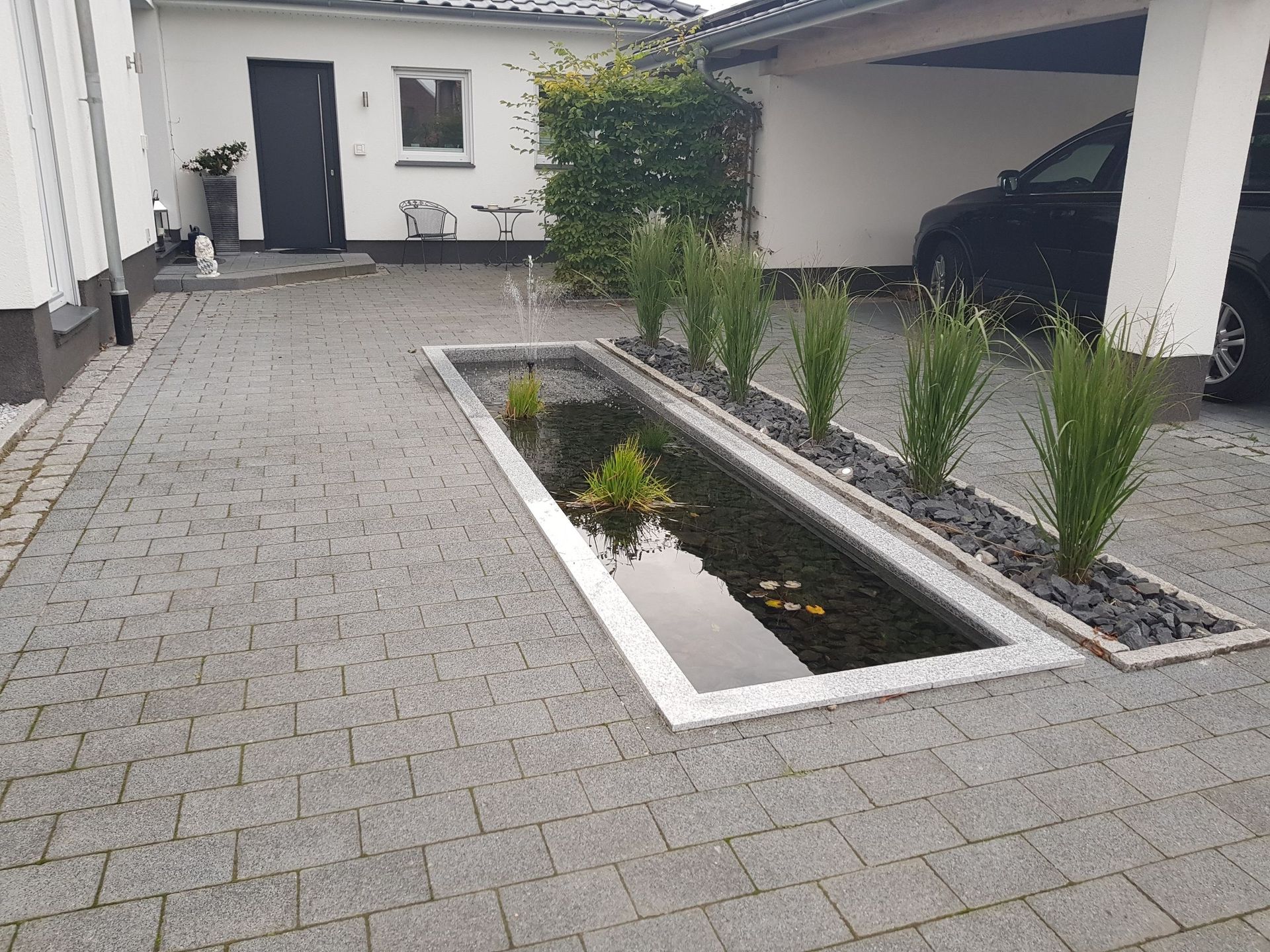 Ein Auto ist in einer Einfahrt neben einem Teich geparkt.