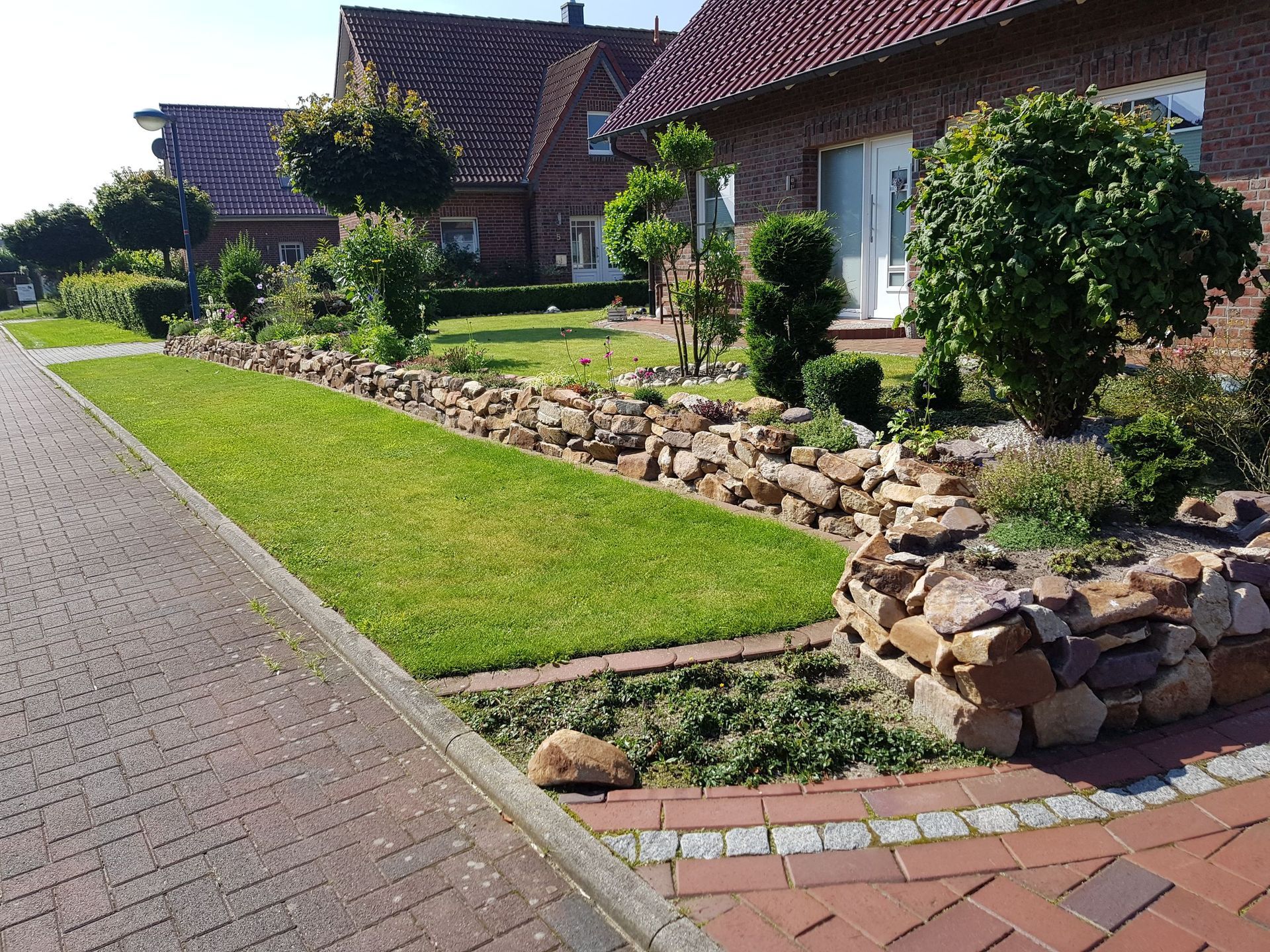 Eine gepflasterte Auffahrt, die zu einem Haus mit einem üppigen grünen Rasen führt