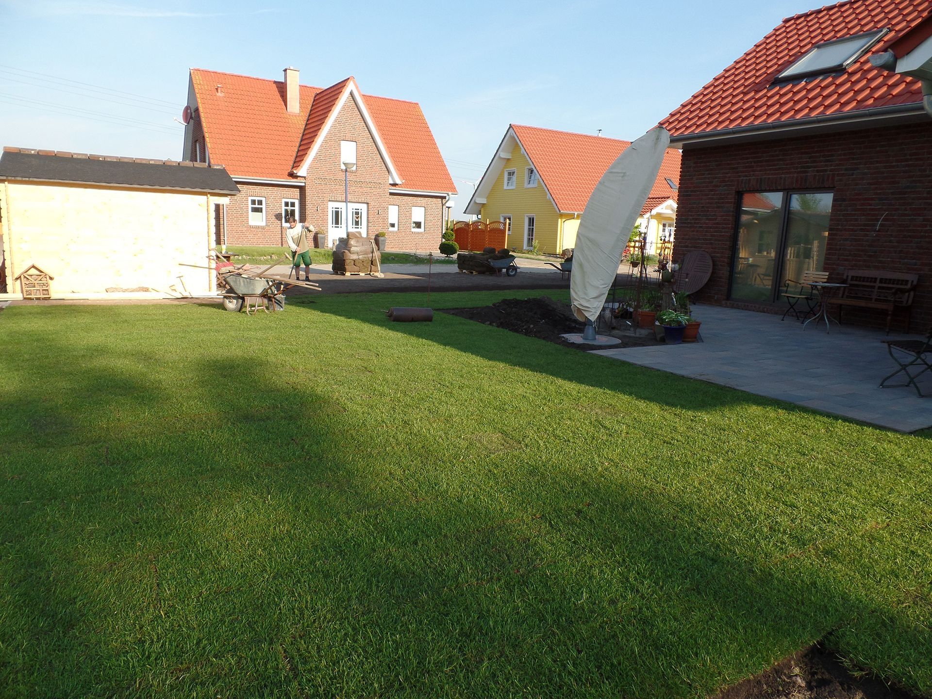 Ein üppiger grüner Rasen vor einem Haus mit rotem Dach