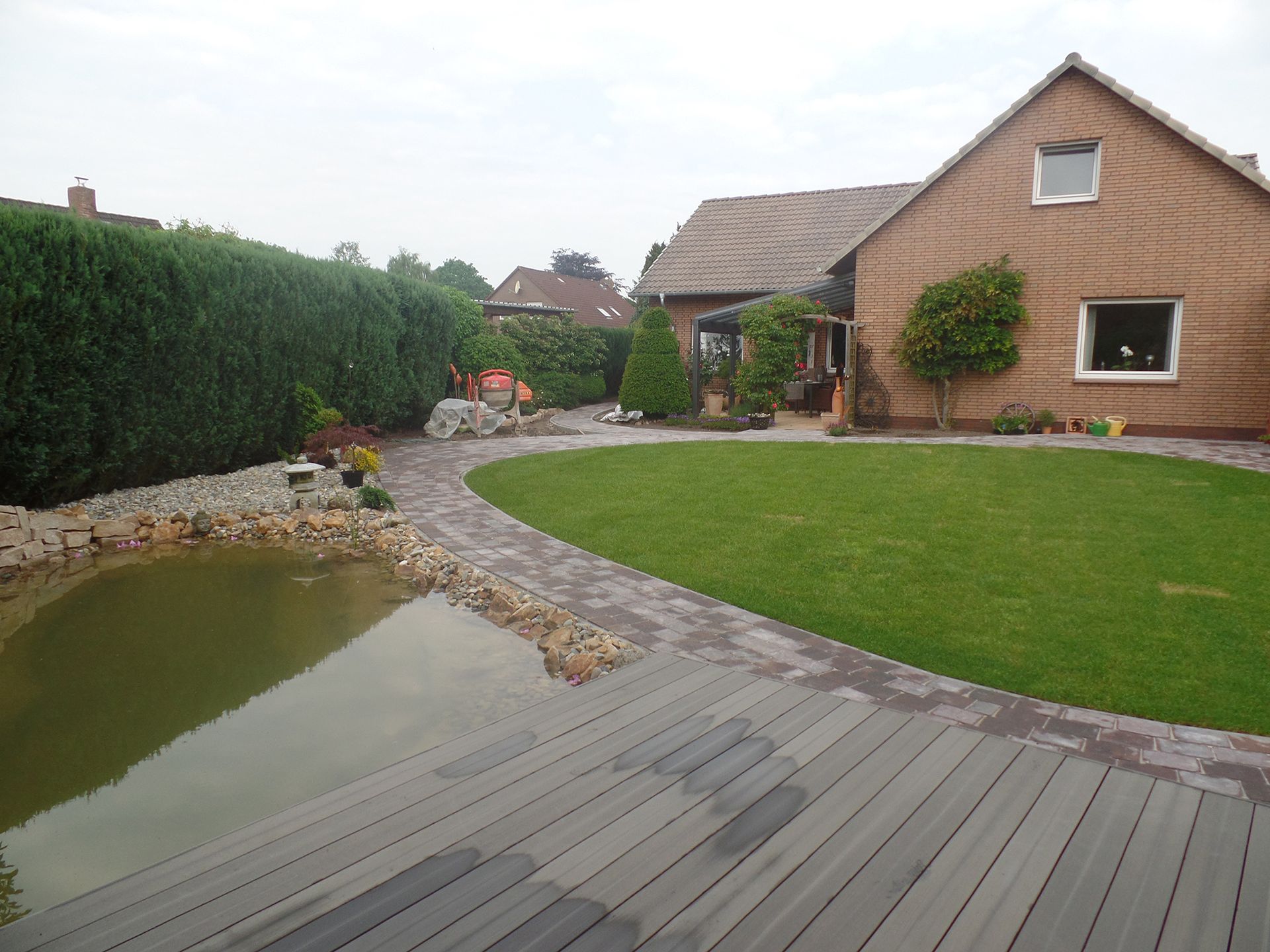 Ein Haus mit großer Wiese und einem Teich davor.